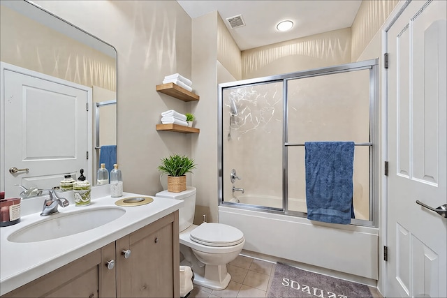 bathroom featuring bath / shower combo with glass door, visible vents, toilet, vanity, and tile patterned floors