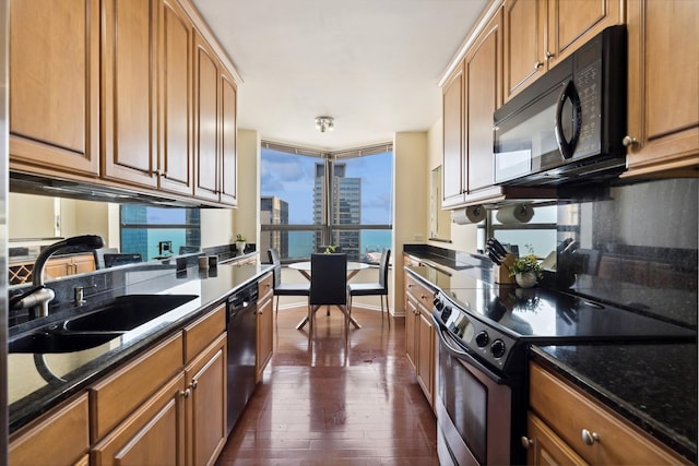 kitchen featuring a view of city, brown cabinets, dark wood finished floors, a sink, and black appliances