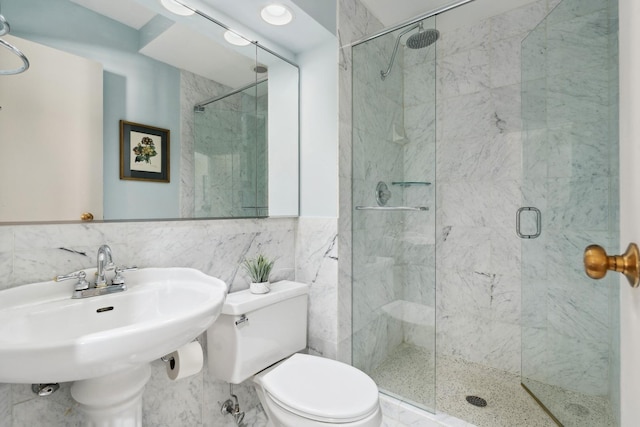 bathroom with a stall shower, a sink, tile walls, and toilet