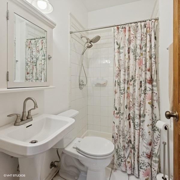 full bath with tiled shower, a sink, and toilet