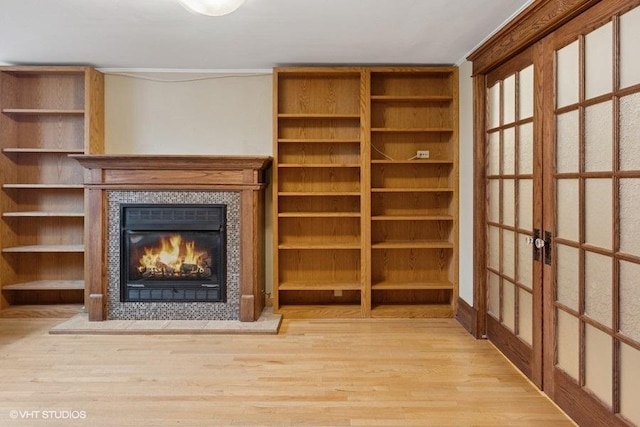 unfurnished living room featuring wood finished floors and a tile fireplace