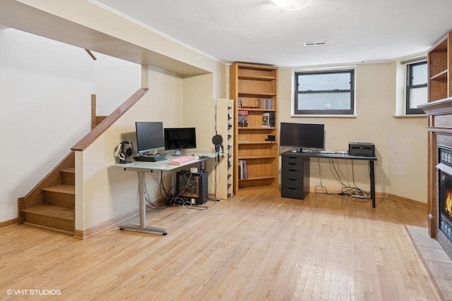 office space with wood finished floors, a fireplace with flush hearth, visible vents, and baseboards