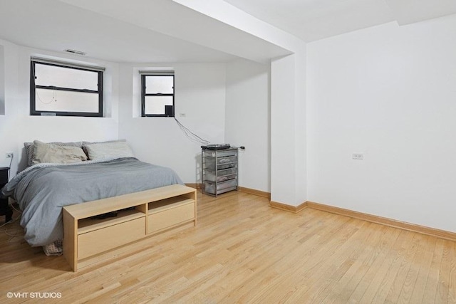 bedroom featuring light wood-style floors, visible vents, and baseboards