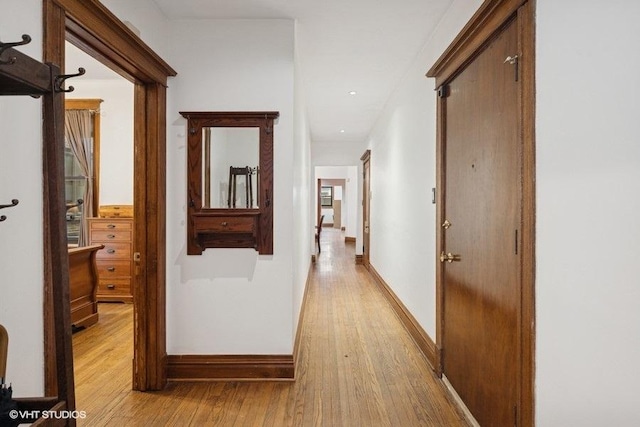 corridor with baseboards and light wood finished floors