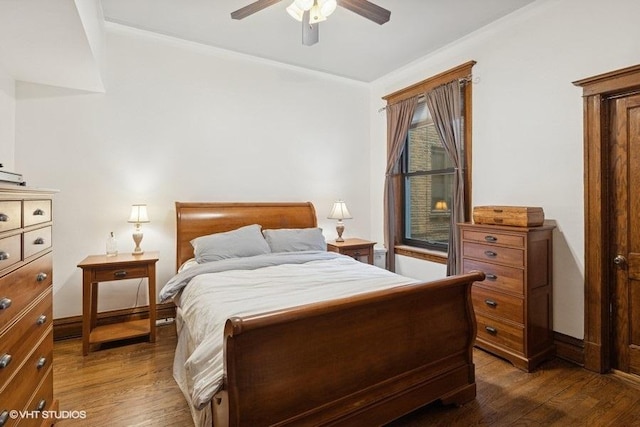 bedroom with crown molding, baseboards, dark wood finished floors, and a ceiling fan