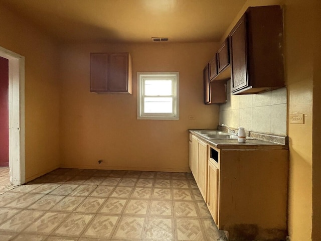 kitchen featuring a sink, light floors, backsplash, and visible vents