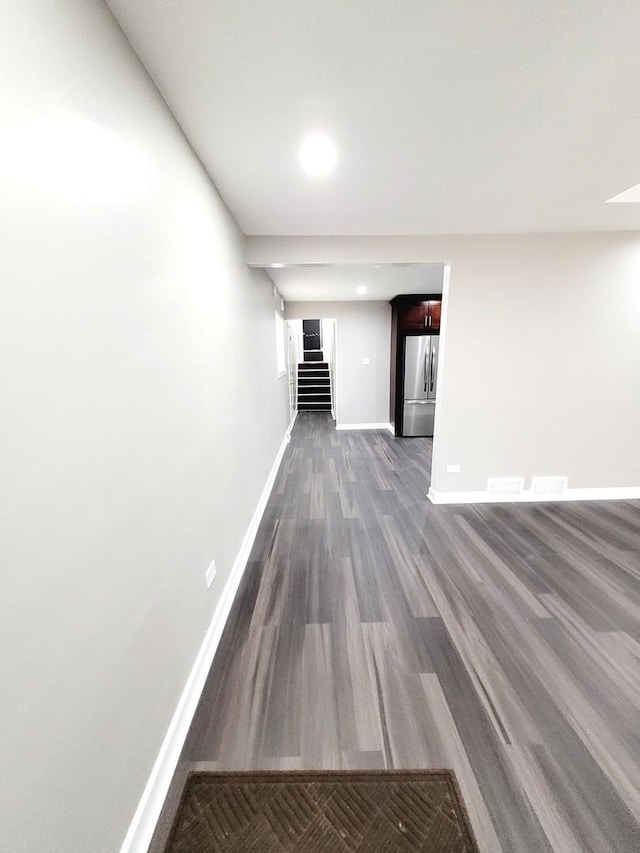 corridor with stairs, baseboards, and dark wood-type flooring