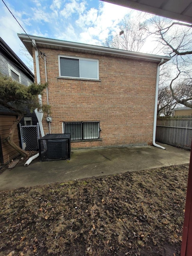 back of property with a patio, brick siding, fence, and central air condition unit