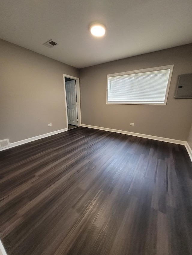 unfurnished room featuring electric panel, dark wood finished floors, visible vents, and baseboards