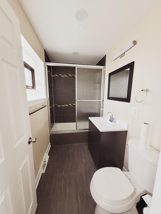 bathroom with toilet, a stall shower, wood finished floors, and vanity