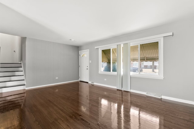 unfurnished living room with stairway, baseboards, visible vents, and wood finished floors