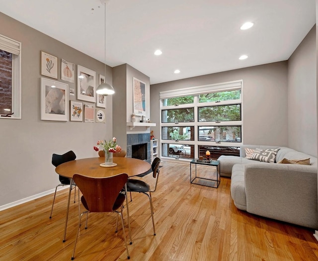 dining area featuring light wood-type flooring, recessed lighting, baseboards, and a tile fireplace