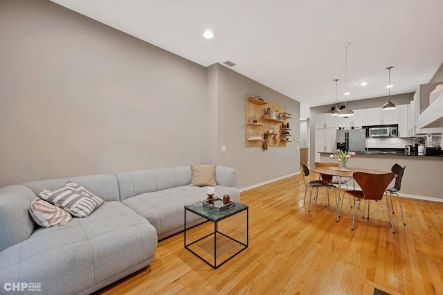 living area featuring baseboards, visible vents, and light wood finished floors