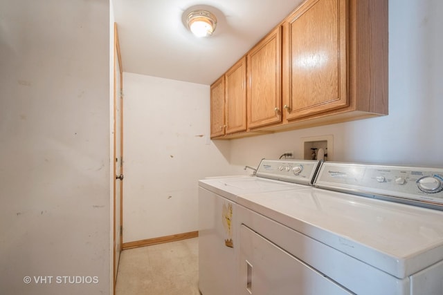 clothes washing area with washing machine and dryer, cabinet space, and baseboards