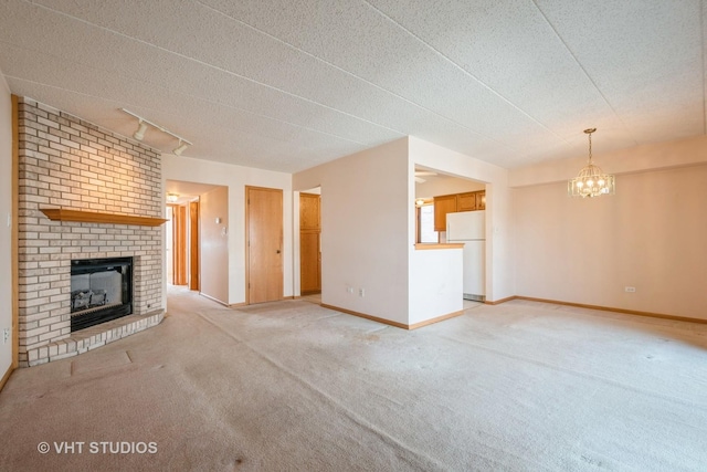 unfurnished living room featuring light colored carpet, a fireplace, a textured ceiling, and baseboards