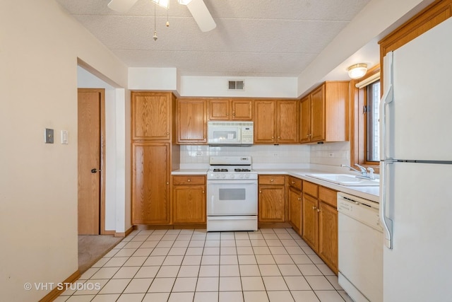 kitchen featuring white appliances, a sink, visible vents, light countertops, and decorative backsplash