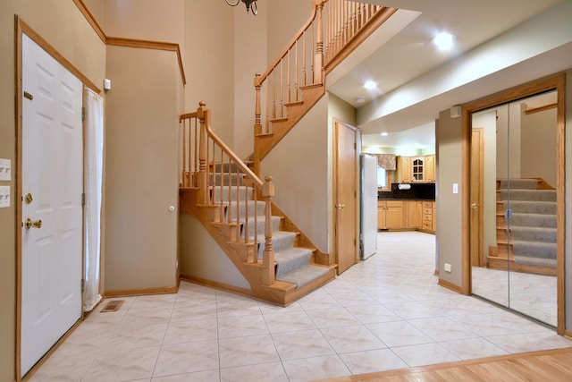 foyer with light tile patterned floors, baseboards, a high ceiling, and stairway