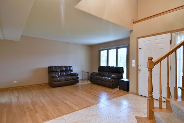 living room with stairway, light wood-style flooring, and baseboards