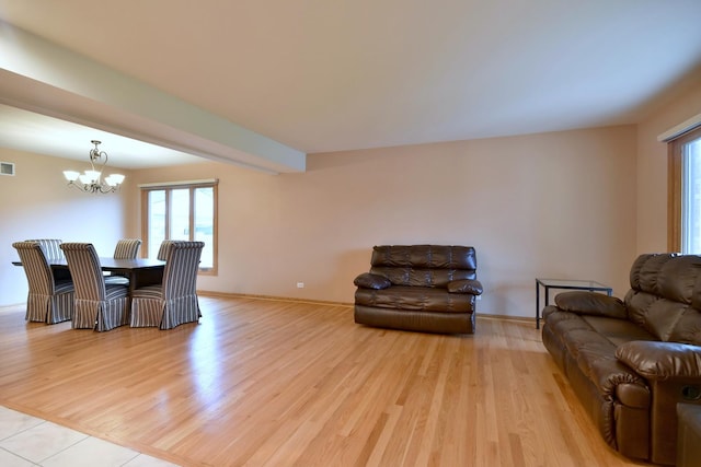 living area featuring baseboards, light wood finished floors, visible vents, and a notable chandelier