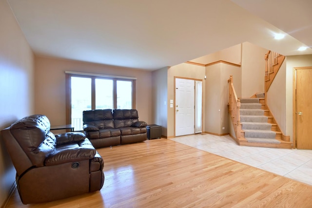 living area with light wood-style flooring, stairs, and baseboards