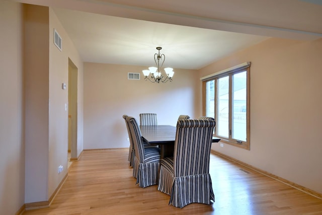 dining space featuring an inviting chandelier, light wood-style flooring, and visible vents