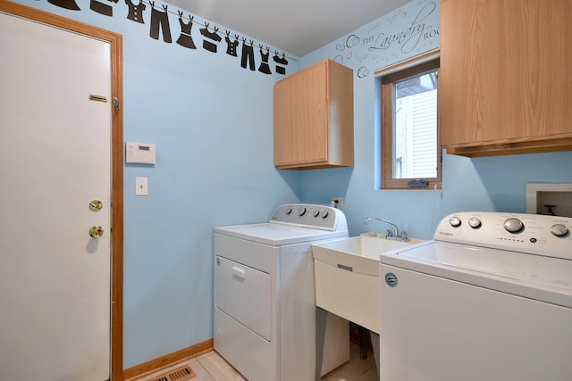 washroom with light tile patterned floors, washing machine and dryer, a sink, baseboards, and cabinet space