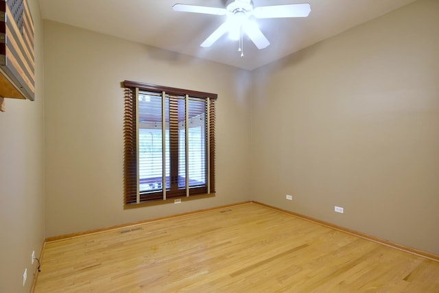 spare room featuring light wood-type flooring, ceiling fan, visible vents, and baseboards