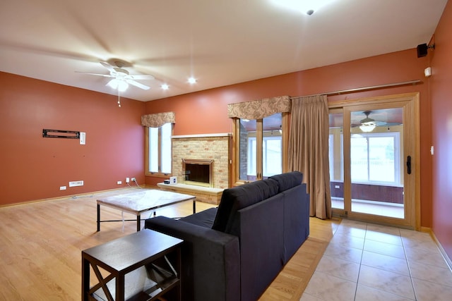 living area with ceiling fan, light tile patterned floors, a fireplace, and baseboards