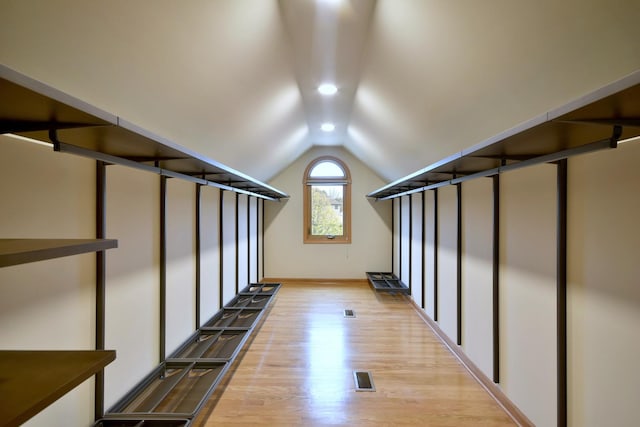 walk in closet featuring visible vents, vaulted ceiling, and wood finished floors