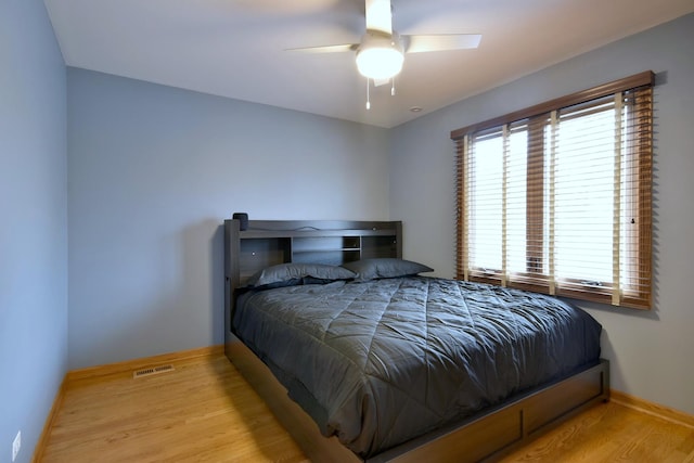 bedroom featuring a ceiling fan, wood finished floors, visible vents, and baseboards