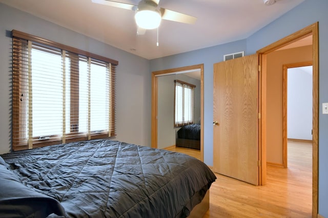 bedroom with light wood finished floors, a closet, visible vents, a ceiling fan, and baseboards