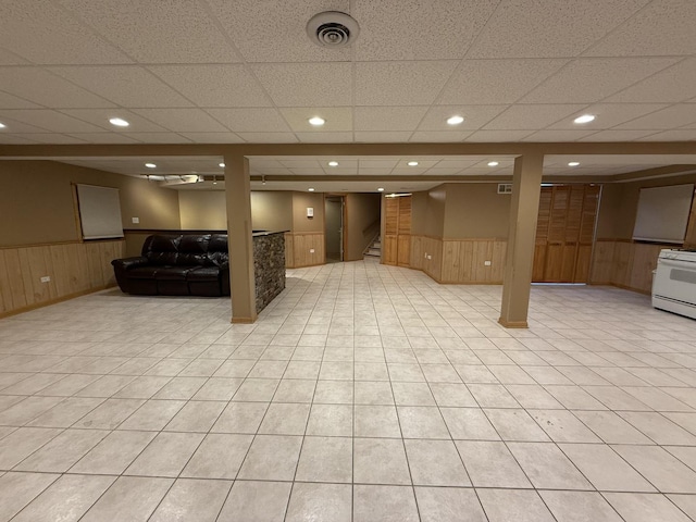 finished basement featuring recessed lighting, wood walls, visible vents, stairway, and wainscoting