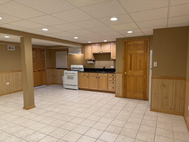 kitchen featuring visible vents, wainscoting, white range with gas cooktop, wall chimney range hood, and a sink