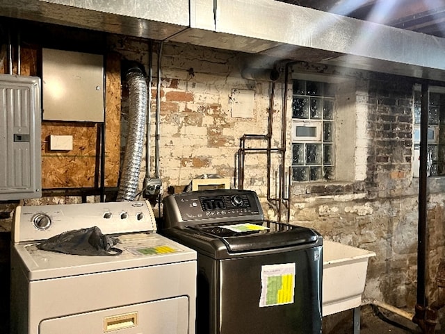 laundry area with laundry area, brick wall, electric panel, and washer and dryer