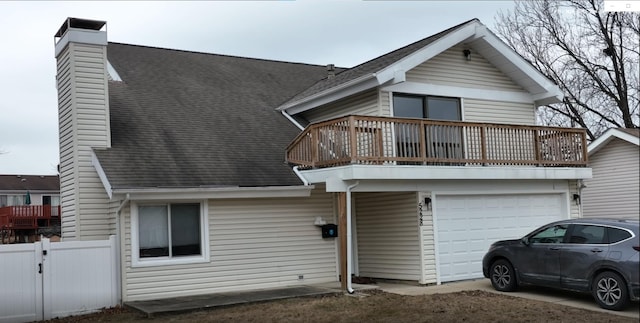 view of front of home featuring a balcony, fence, driveway, roof with shingles, and a chimney