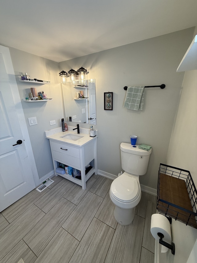 bathroom with visible vents, toilet, wood tiled floor, vanity, and baseboards