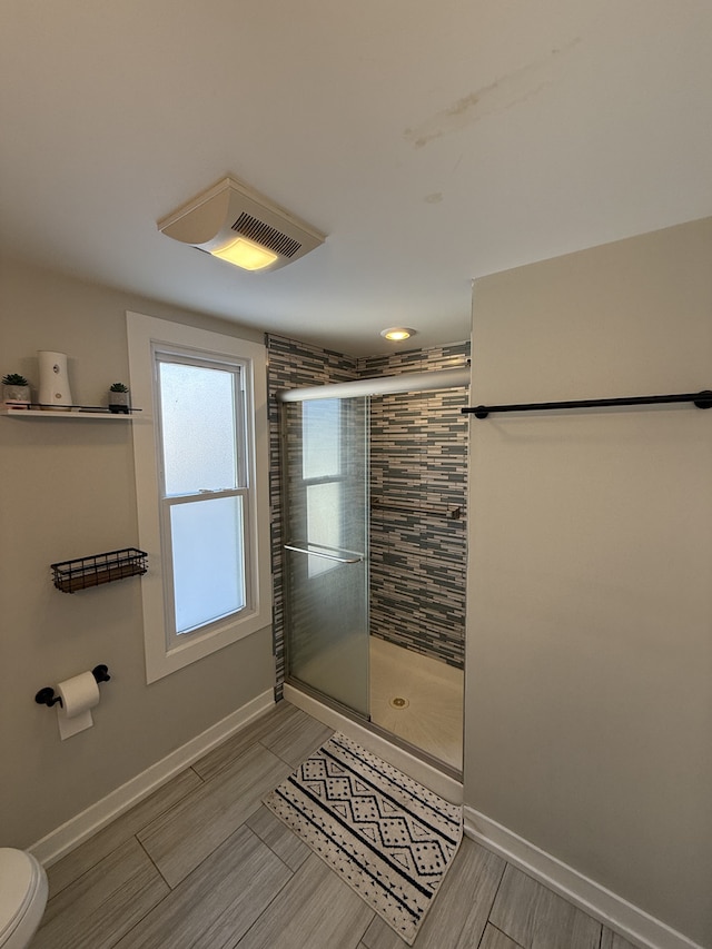 bathroom with toilet, a stall shower, baseboards, and visible vents