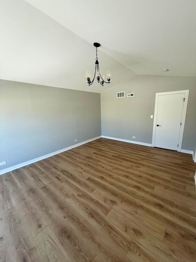 unfurnished dining area with a chandelier, lofted ceiling, visible vents, and wood finished floors