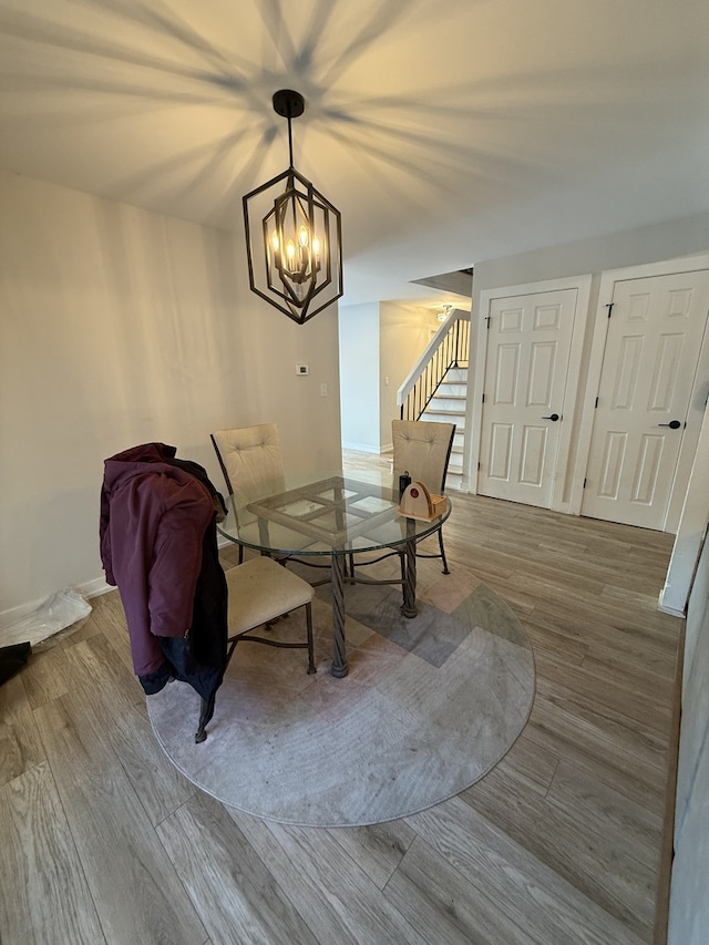 unfurnished dining area with a notable chandelier, stairway, baseboards, and wood finished floors