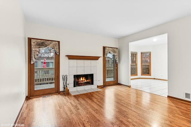 unfurnished living room featuring a fireplace, wood finished floors, visible vents, and baseboards