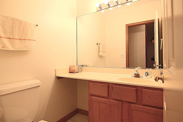 bathroom with tile patterned flooring, baseboards, vanity, and toilet