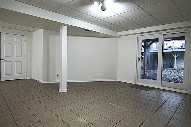 basement with a drop ceiling and baseboards