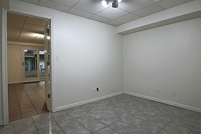 tiled spare room with baseboards and a drop ceiling