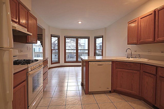 kitchen featuring light countertops, light tile patterned flooring, a sink, white appliances, and a peninsula