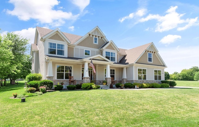 craftsman house with stone siding, a porch, and a front yard