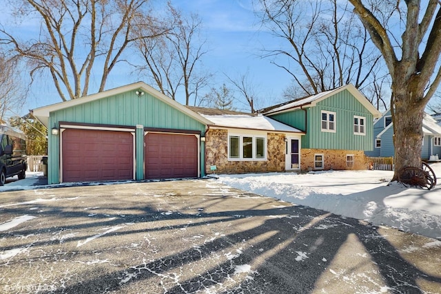 split level home featuring stone siding, driveway, and an attached garage