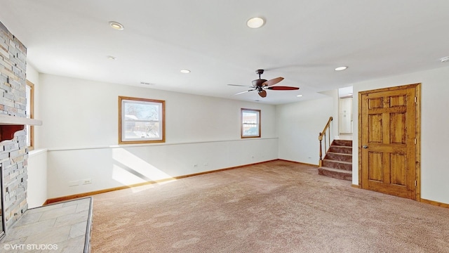 spare room featuring recessed lighting, stairway, a large fireplace, light carpet, and baseboards