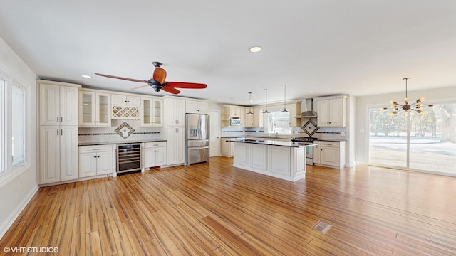 kitchen with wine cooler, stainless steel appliances, dark countertops, visible vents, and wall chimney range hood