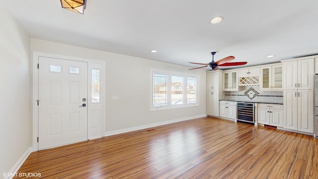 foyer entrance featuring light wood-type flooring, beverage cooler, baseboards, and recessed lighting