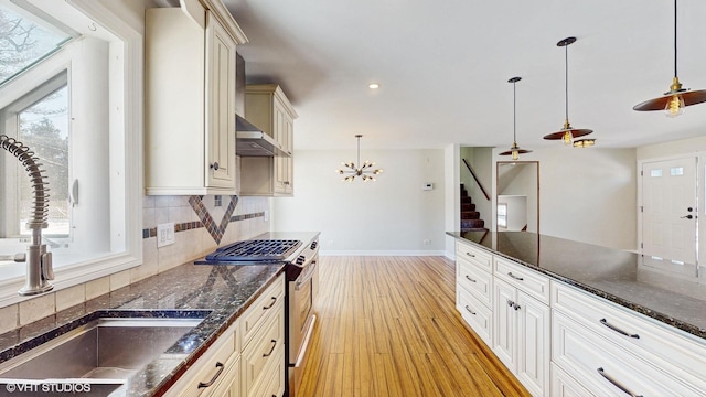 kitchen with stainless steel gas stove, light wood finished floors, a wealth of natural light, and backsplash